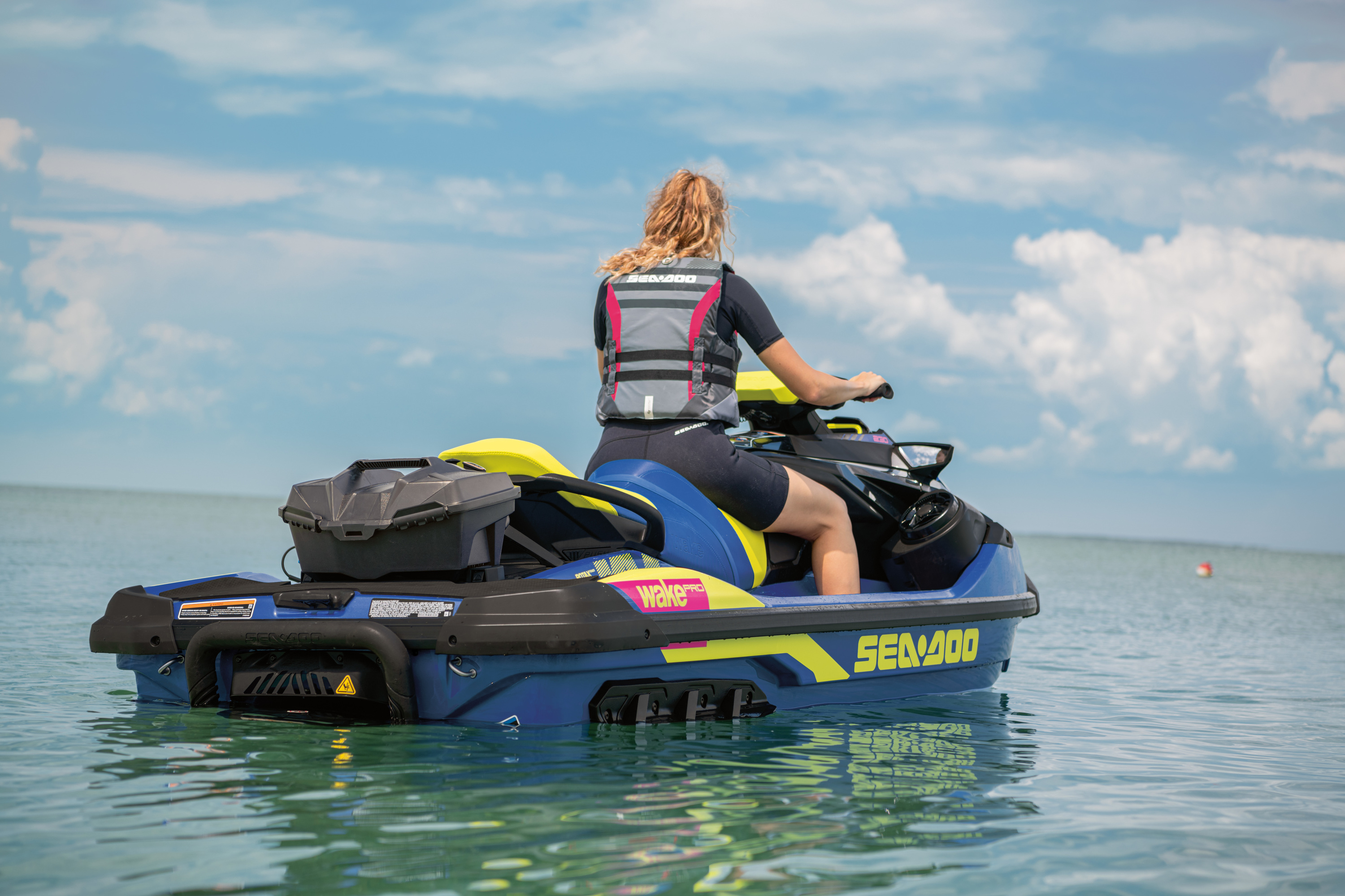 Lady on Sea Doo Wake Pro 230 in blue and yellow with cooler on the back
